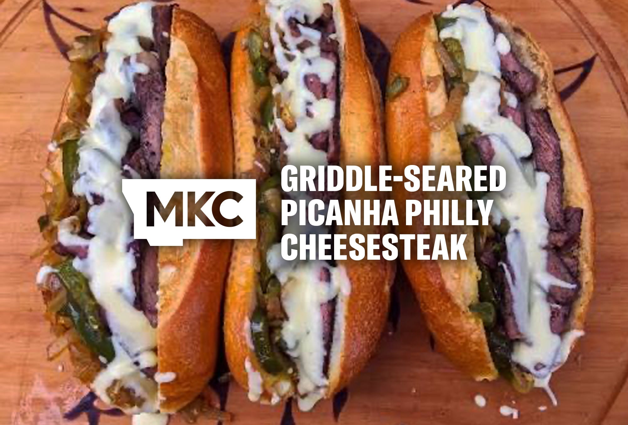 Three griddle‑seared picanha Philly cheesesteak sandwiches on toasted rolls with beef, melted cheese, onions, and peppers.