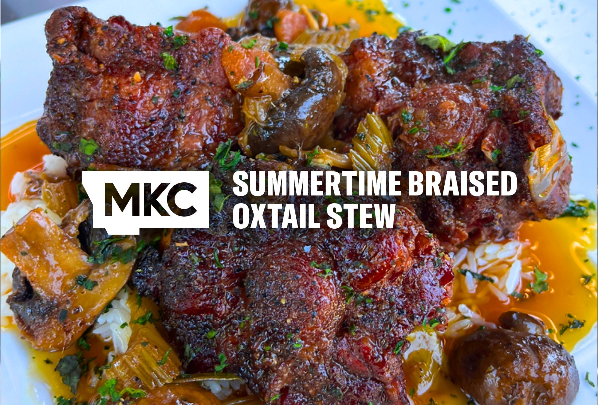 Braised oxtail stew served over rice with vegetables and herbs in a rich, glossy sauce.