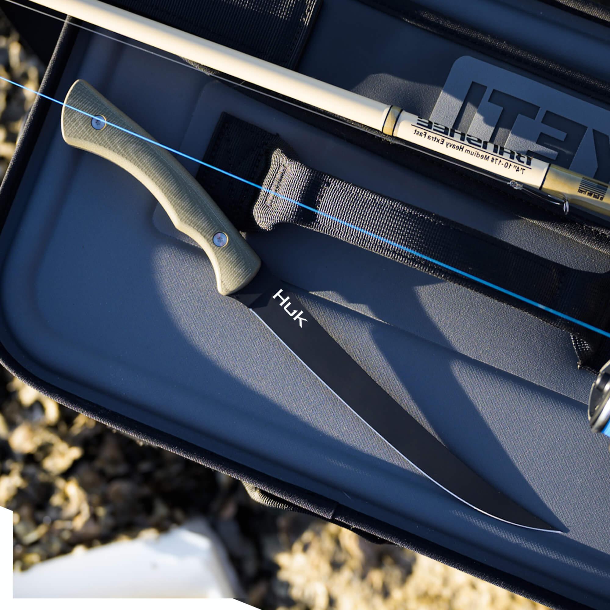 HUK Flathead Fillet knife with a sleek blade and ergonomic handle, resting on a fishing tackle box.