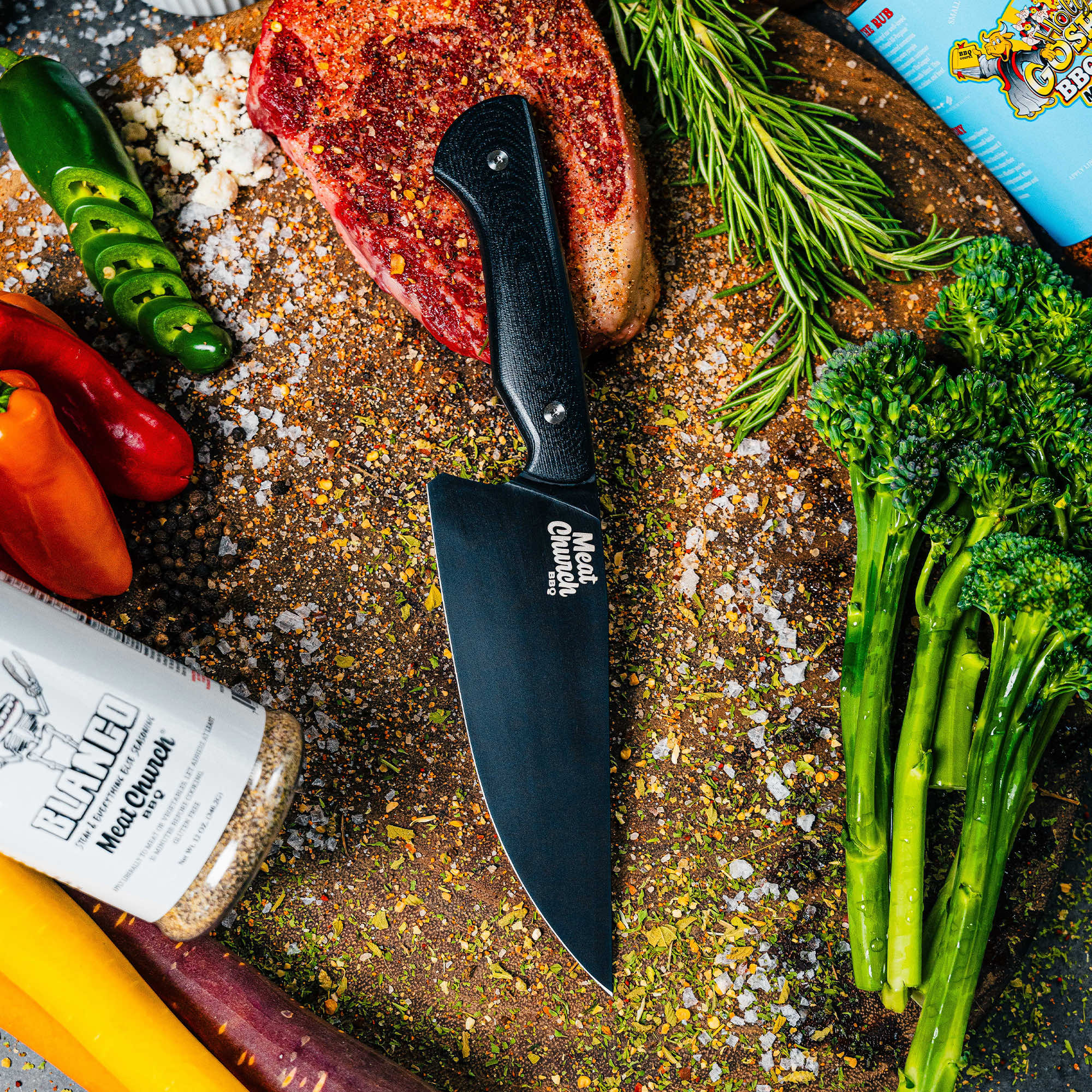 Meat Church Chef Knife on a wooden cutting board surrounded by fresh vegetables and spices, ideal for culinary tasks.