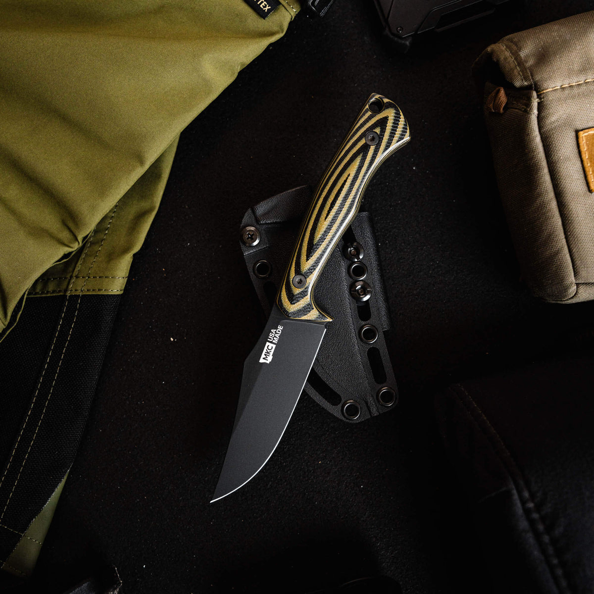 Triumph Pro knife in green and black with a sleek blade, displayed on a tactical background with gear.