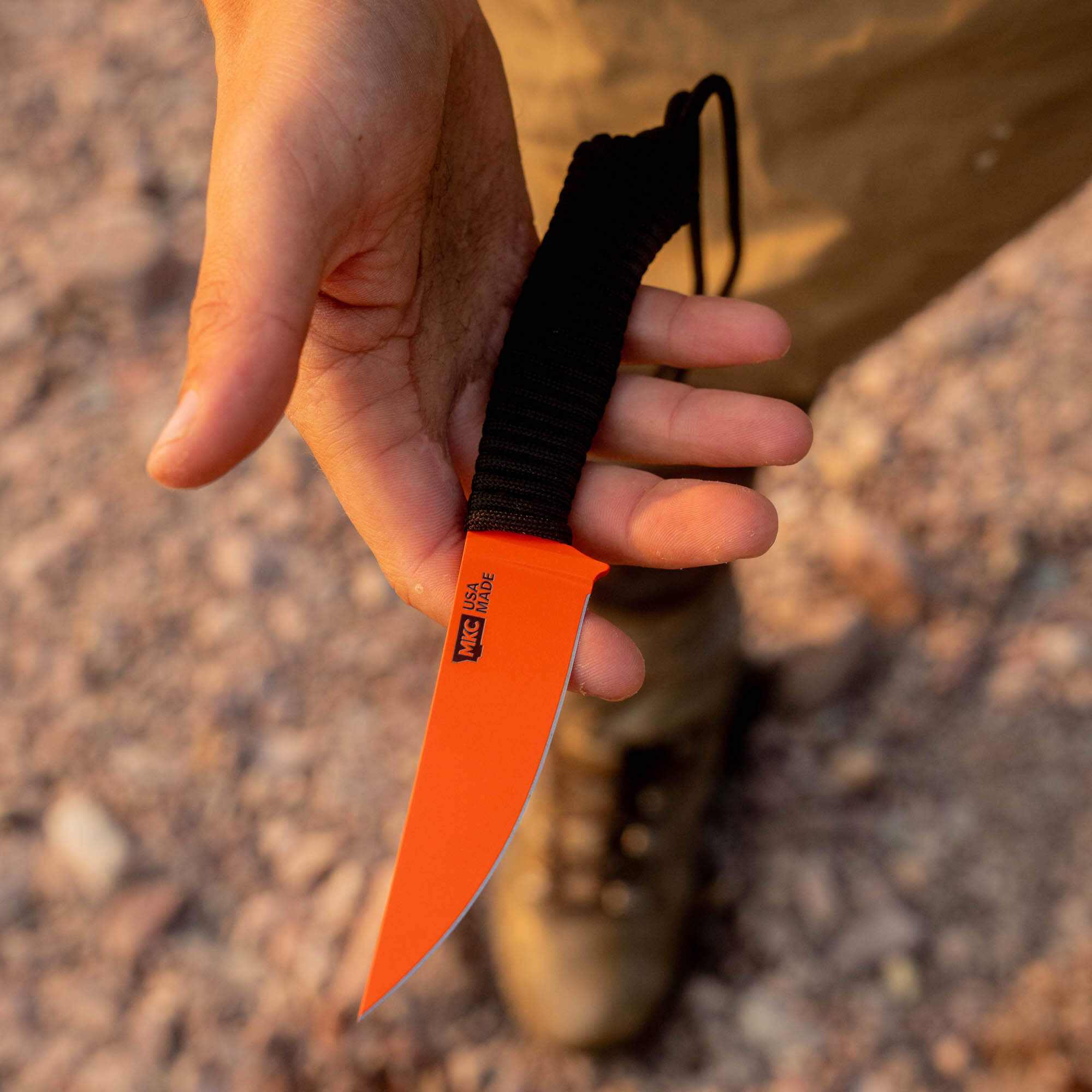 SPEEDGOAT 2.0 knife with blaze orange Cerakote finish held in a hand, featuring a textured grip and a durable blade.