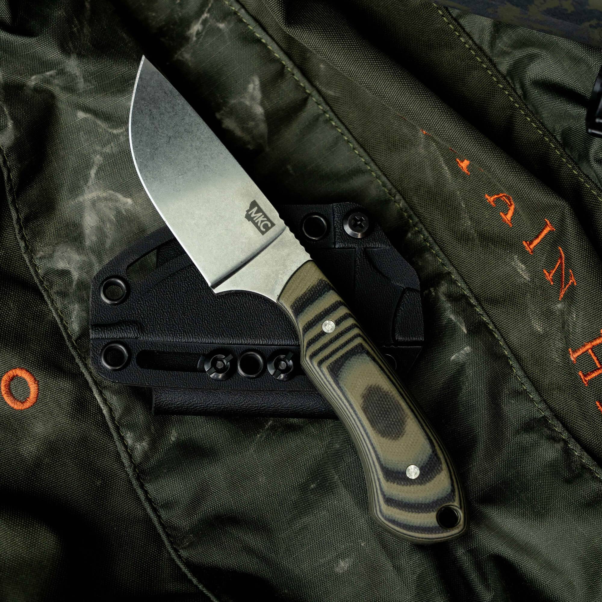 SOLD OUT MKC Elk Knife with a durable blade and camo handle, resting on a tactical background, ideal for outdoor enthusiasts.