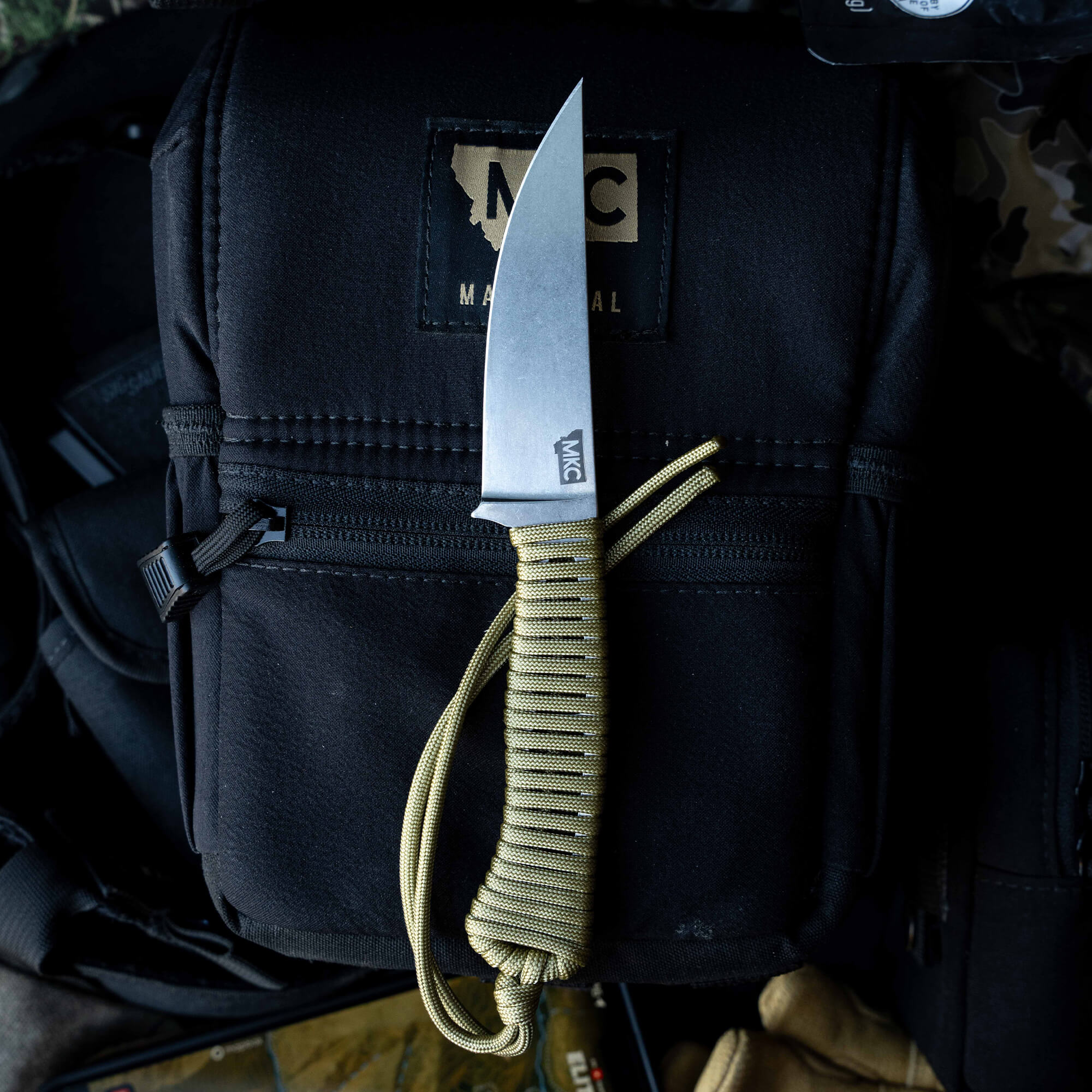 ONX Hunt Magnacut Speedgoat 2.0 knife with a sleek blade and paracord handle on a tactical bag, ideal for outdoor use.