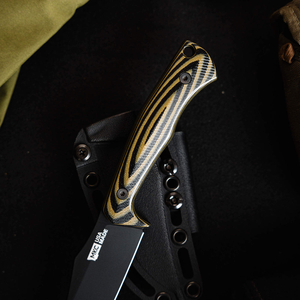 Close-up of the TRIUMPH PRO knife featuring a green and black patterned handle and a sleek black blade.