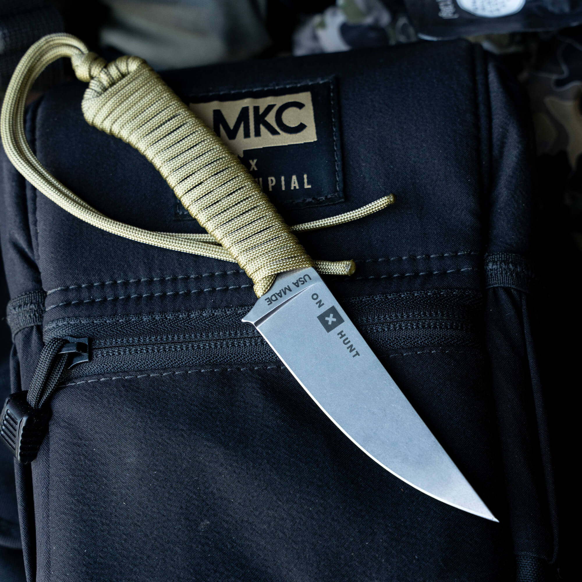 ONX Hunt Magnacut Speedgoat 2.0 knife with a textured handle, resting on a black tactical bag, showcasing its sleek design.