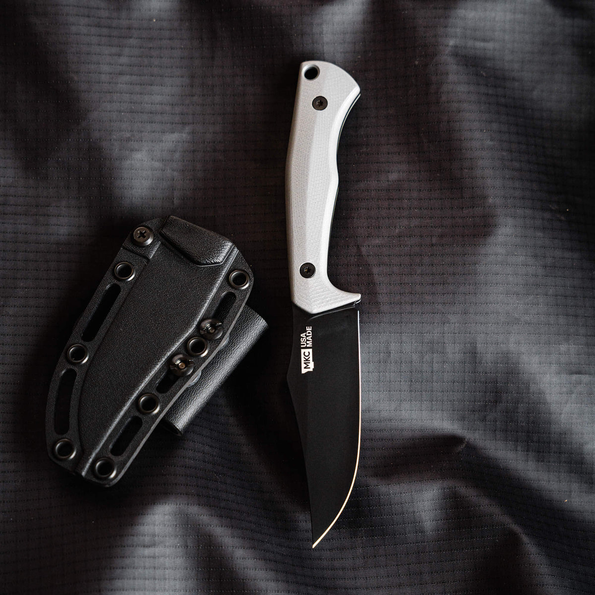 Grey Triumph Pro knife with a black blade and matching sheath, designed for durability and outdoor use.
