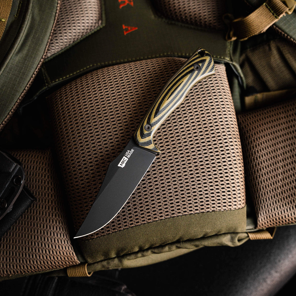 Triumph Pro knife in green and black with a sleek blade, resting on a tactical backpack. Ideal for outdoor use.