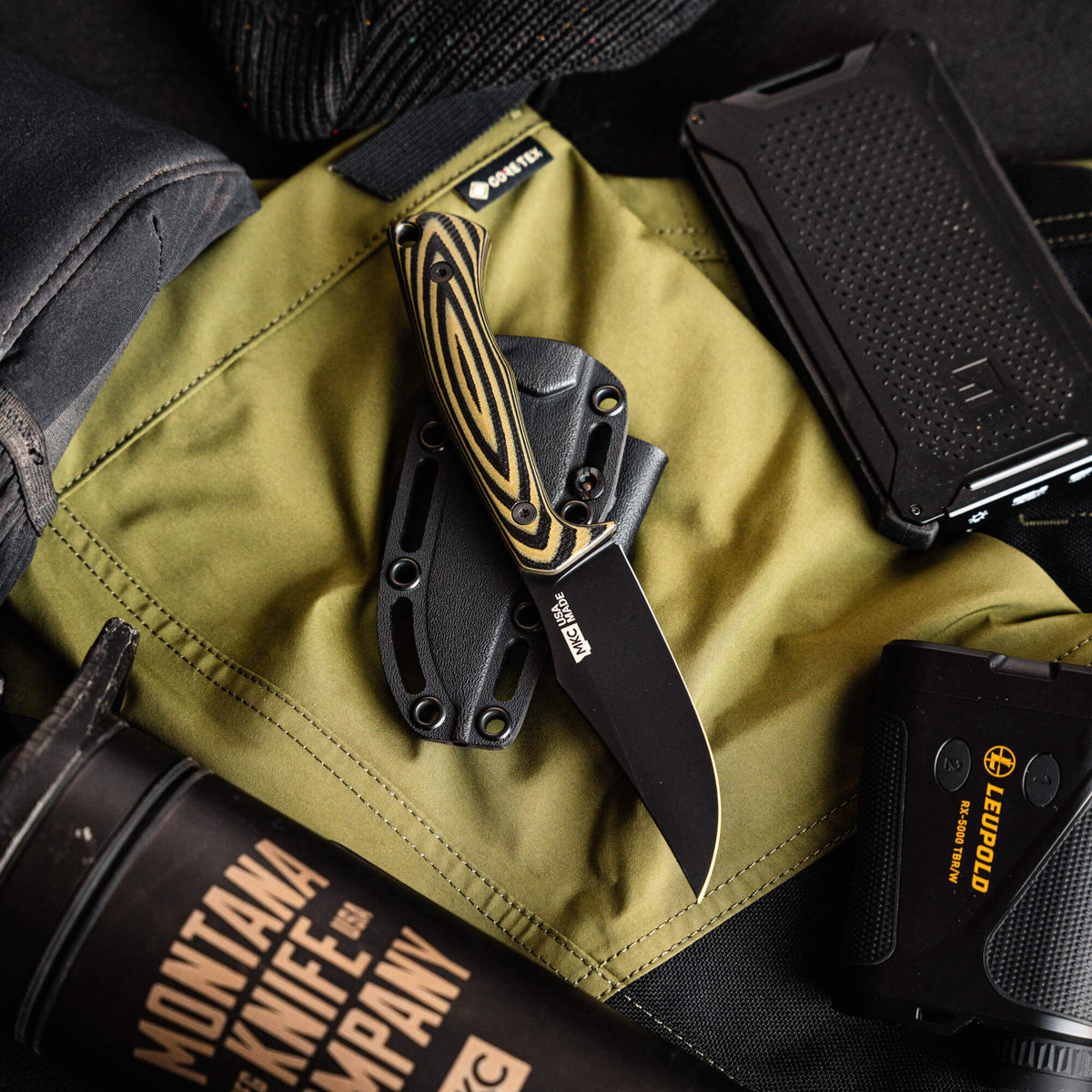Triumph Pro knife in green and black, featuring a fixed blade and textured handle, displayed on tactical gear.