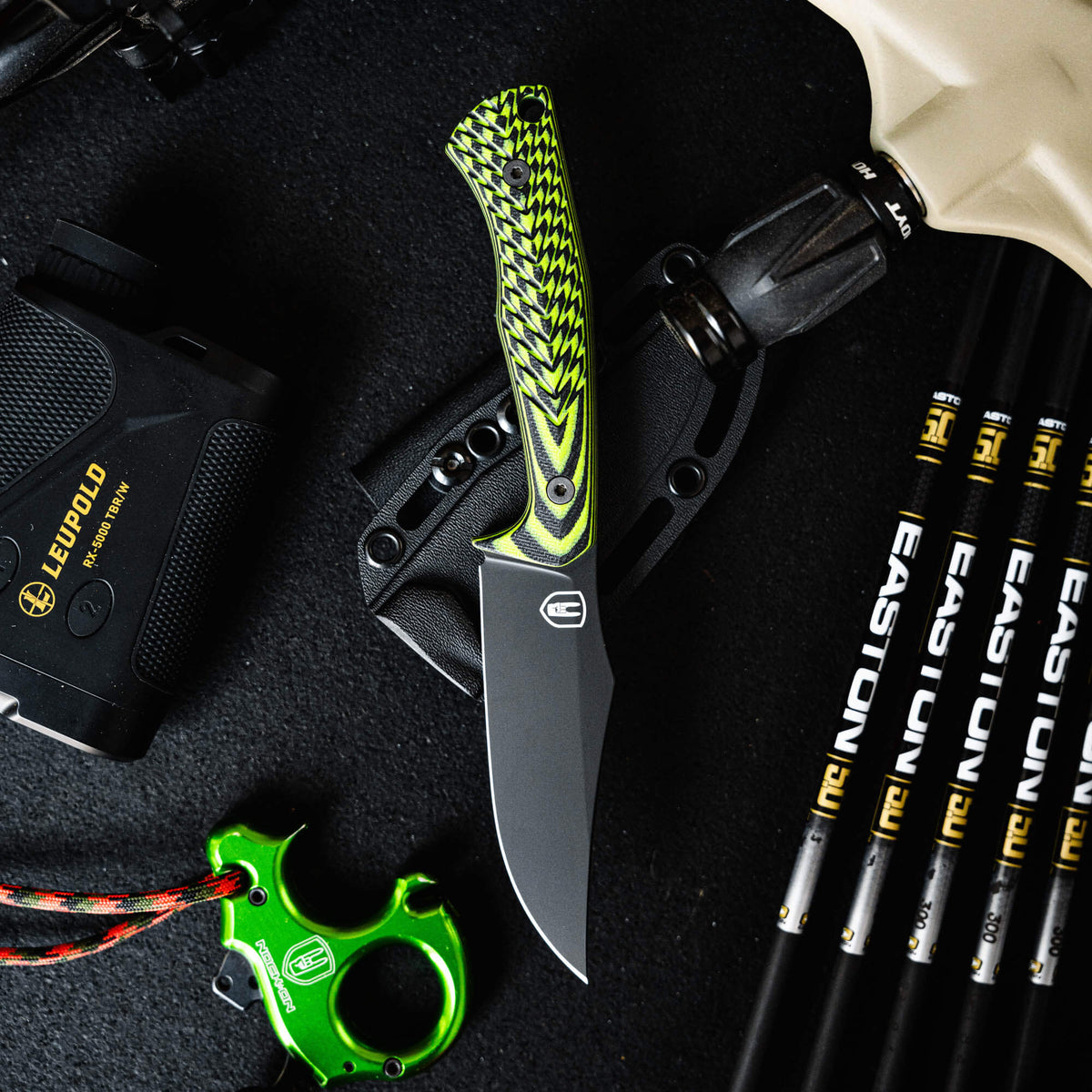 Triumph Pro knife in neon green and black with a sleek blade, surrounded by archery gear and accessories.