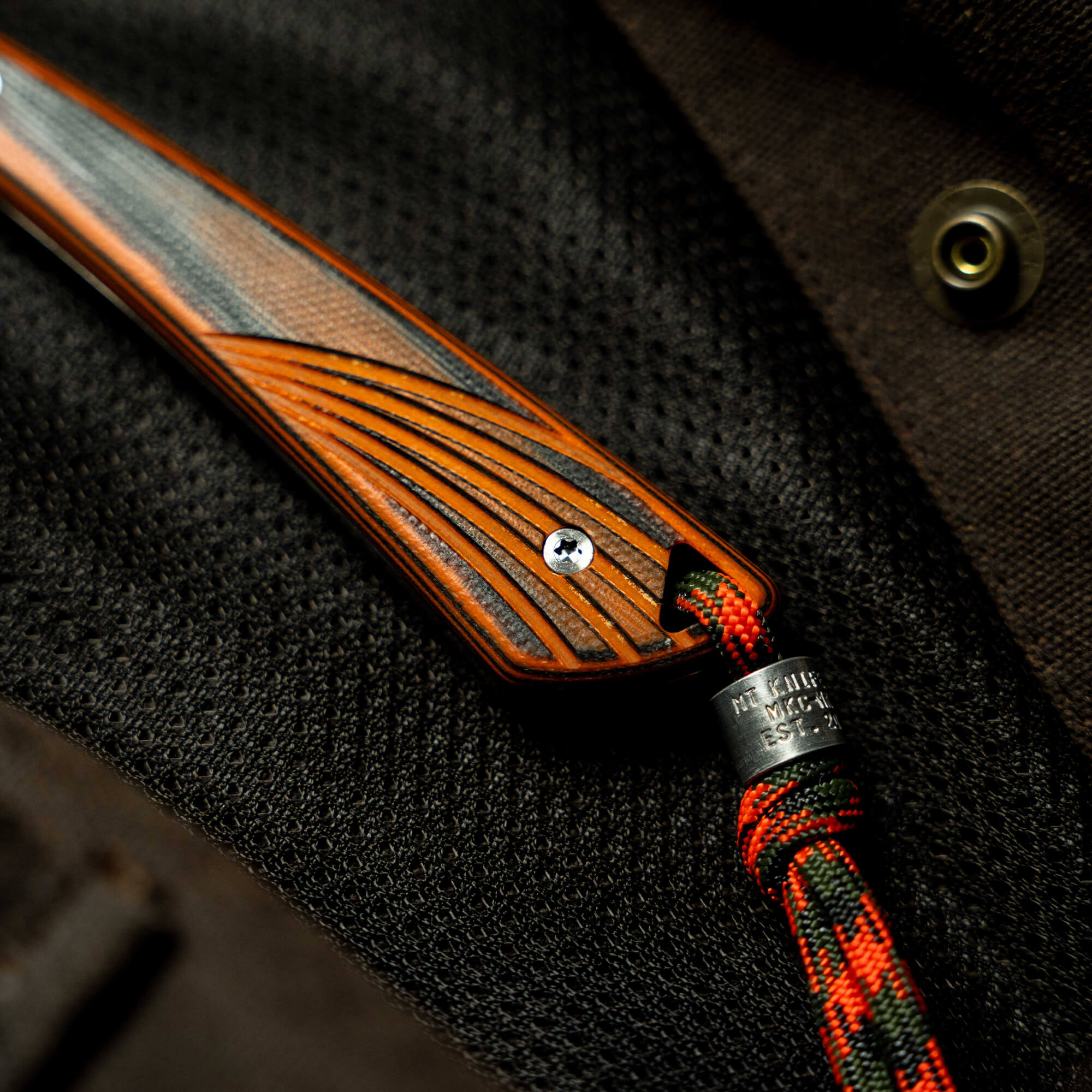 Close-up of the CHÊNE - FREEZOUT knife handle featuring a textured wood design and a paracord lanyard.