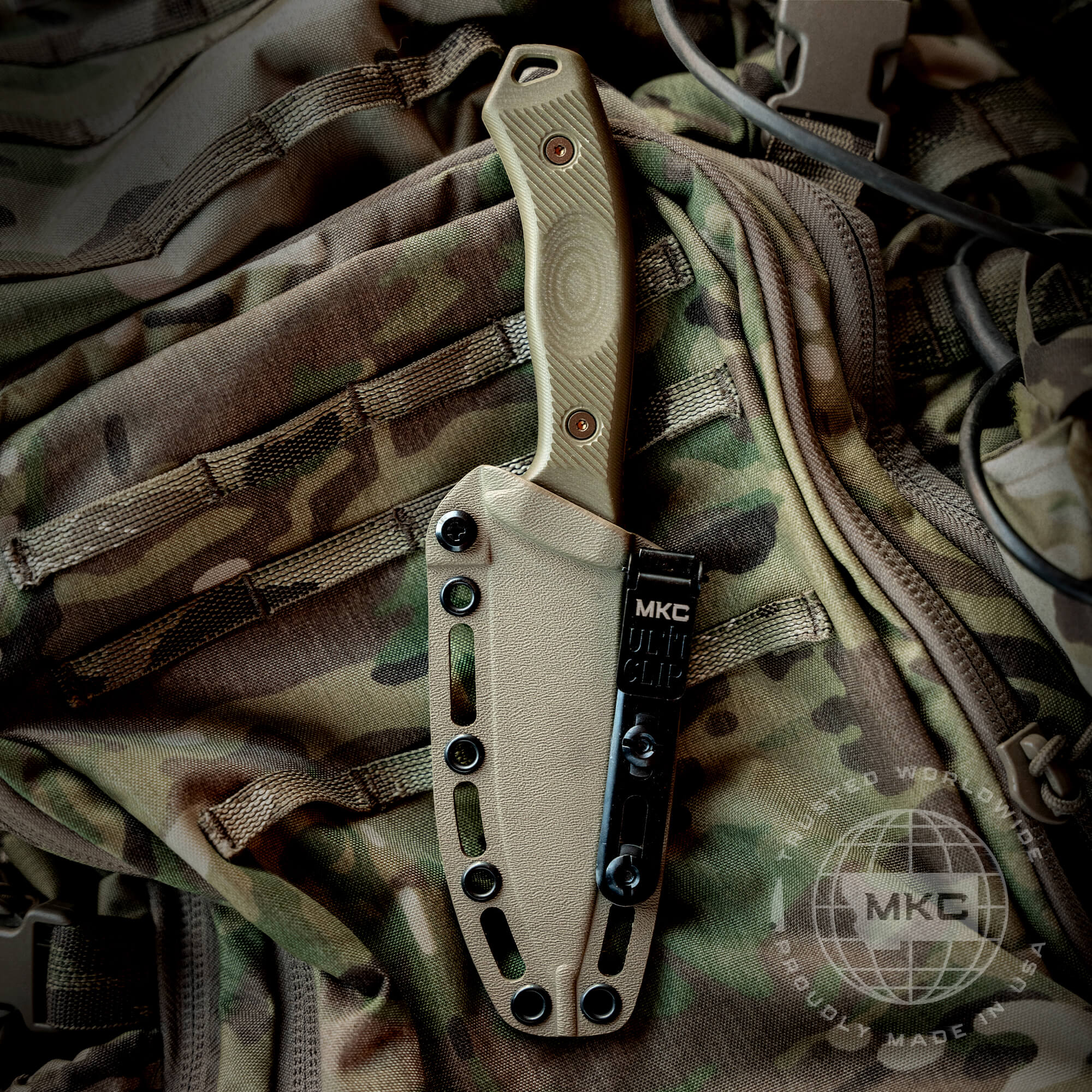 Alt text: "Coyote-colored TF24 Kydex sheath attached to a camouflage backpack, featuring a secure MKC multi-clip system and visible knife handle with wood texture finish."
