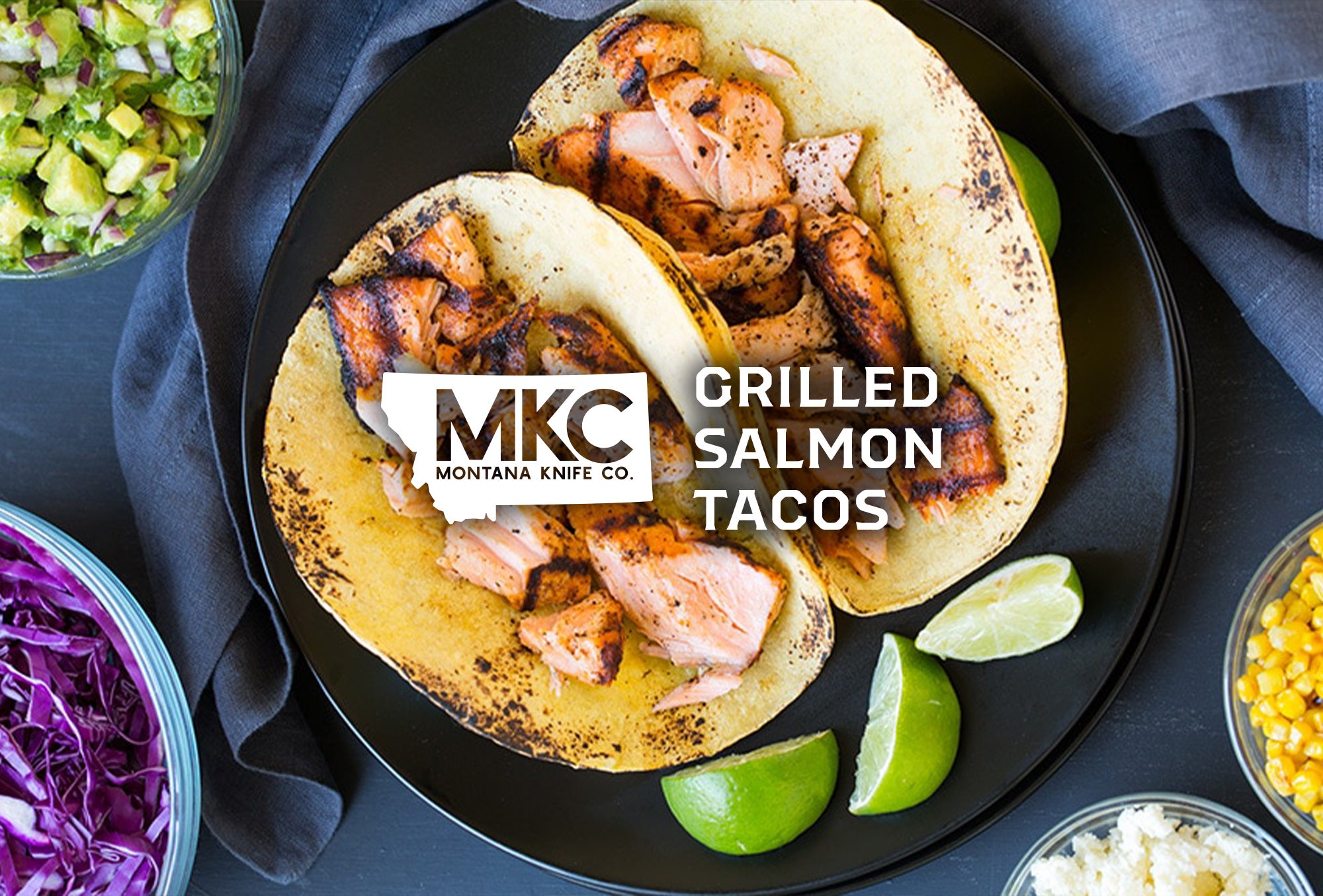 A top-down view of a plate of two delicious salmon tacos garnished with lime wedges.