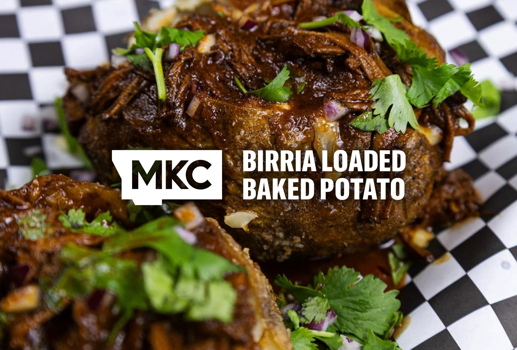 Close-up image of a birria baked potato loaded with shredded beef, consommé, melted cheese, and cilantro on a crispy russet.