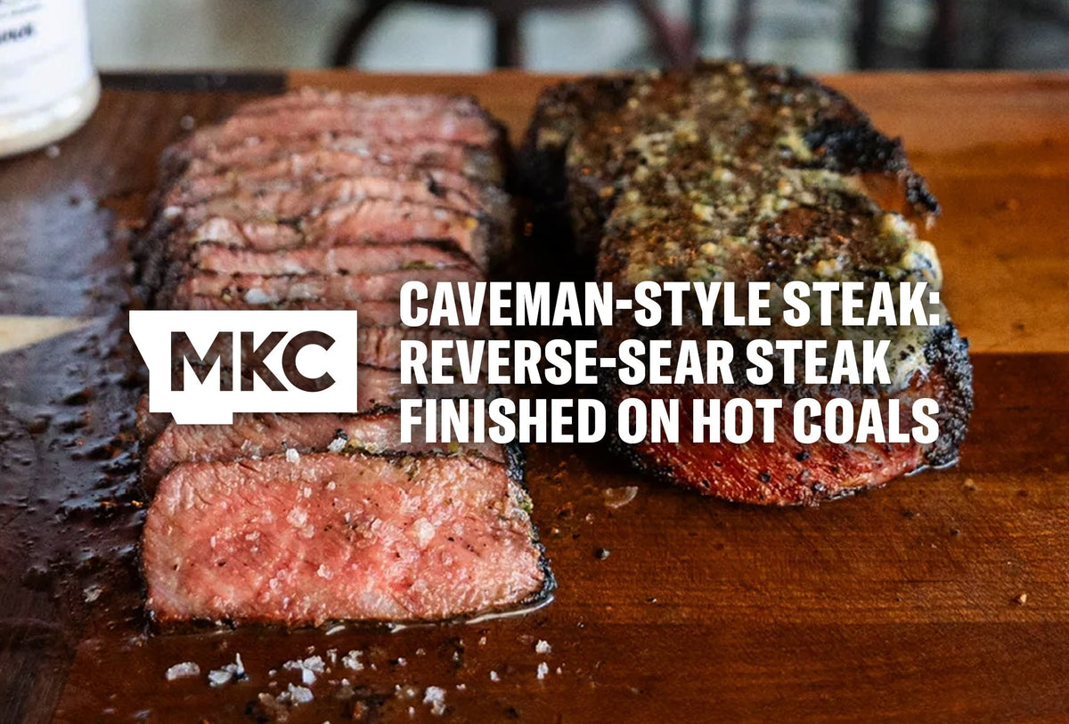 Caveman-style reverse-seared medium-rare steak on a wooden board with coarse salt.