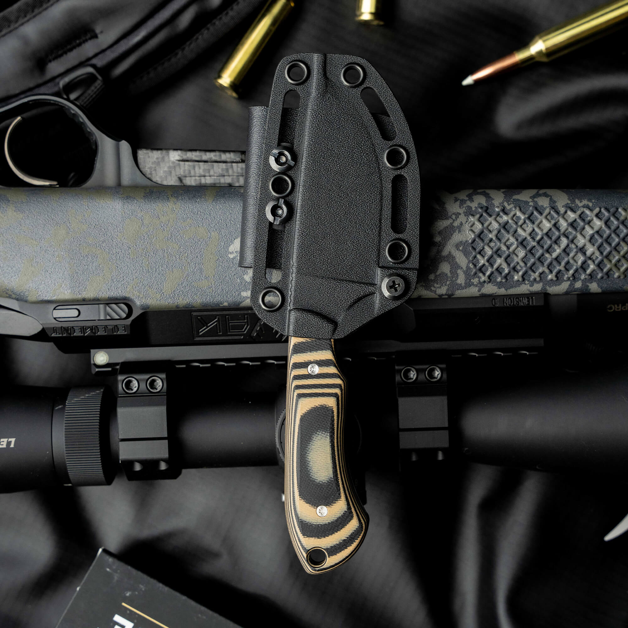 Montana Knife Company's Live Wild Elk Knife in sheath, displayed on a rifle, showcasing its rugged design and craftsmanship.