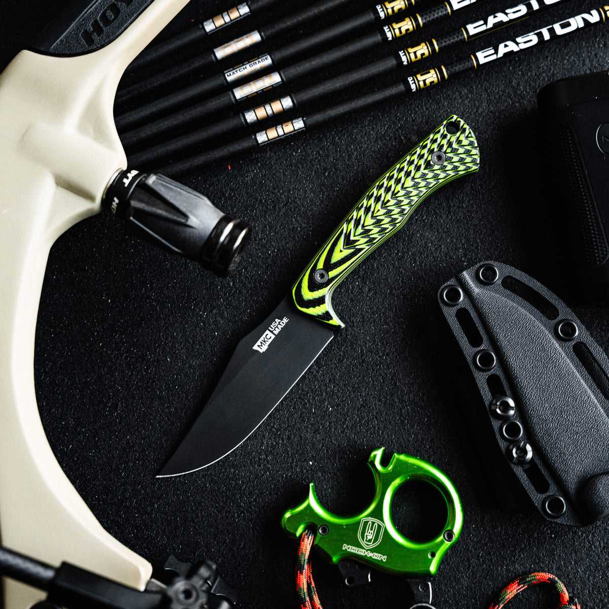 Triumph Pro knife in neon green and black with a sleek blade, surrounded by archery gear and accessories.