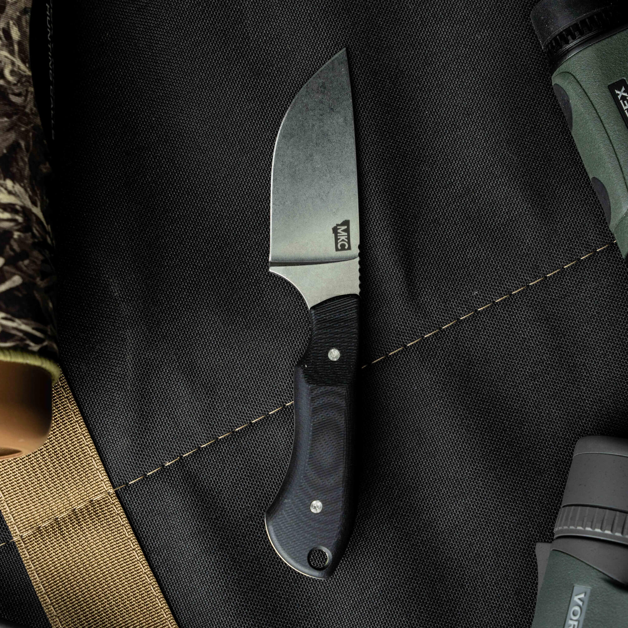 Sleek MKC Elk Knife with a black blade and textured handle, designed for outdoor enthusiasts and hunters.