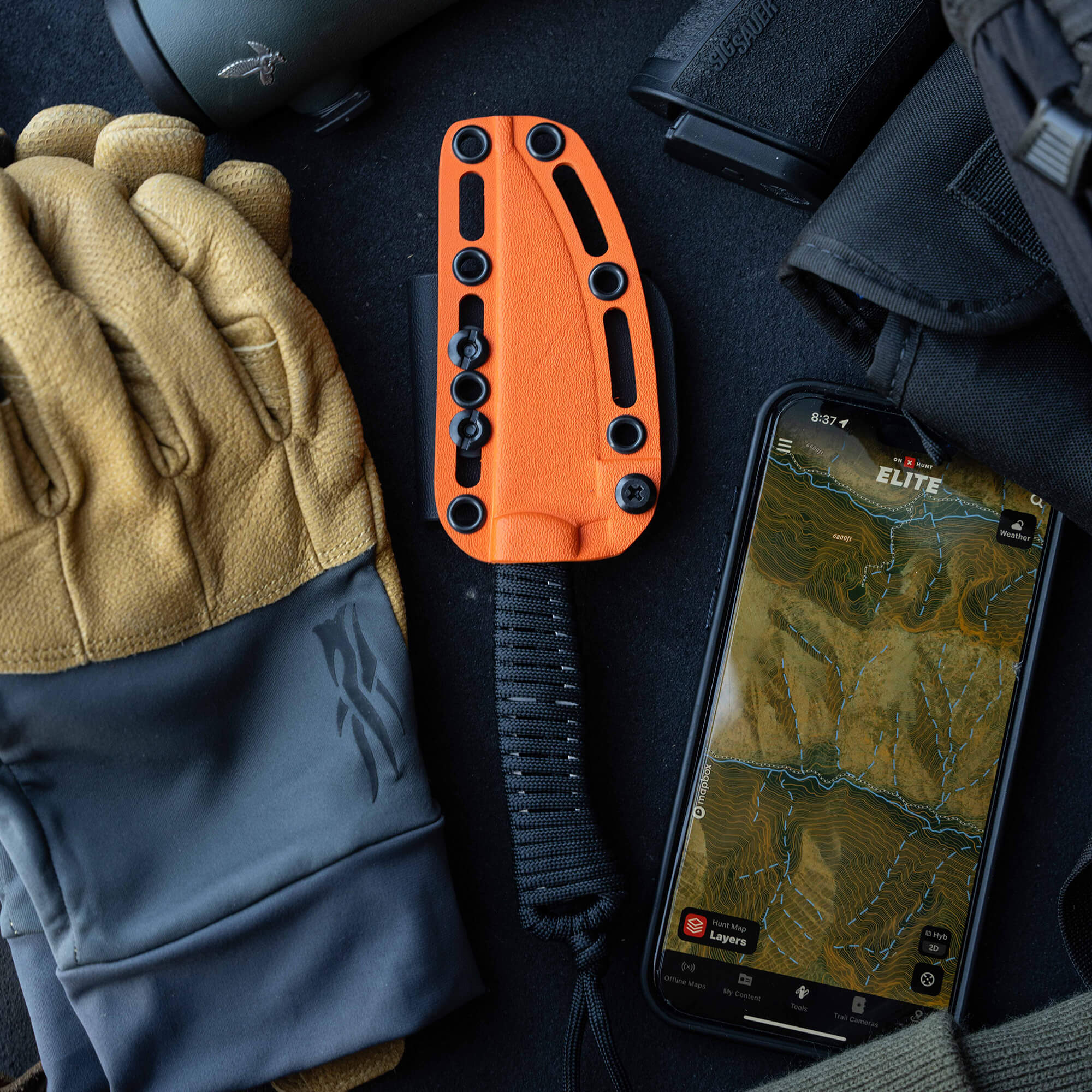 ONX Hunt Magnacut Speedgoat 2.0 knife with orange handle, gloves, gear, and smartphone displaying a topographic map.