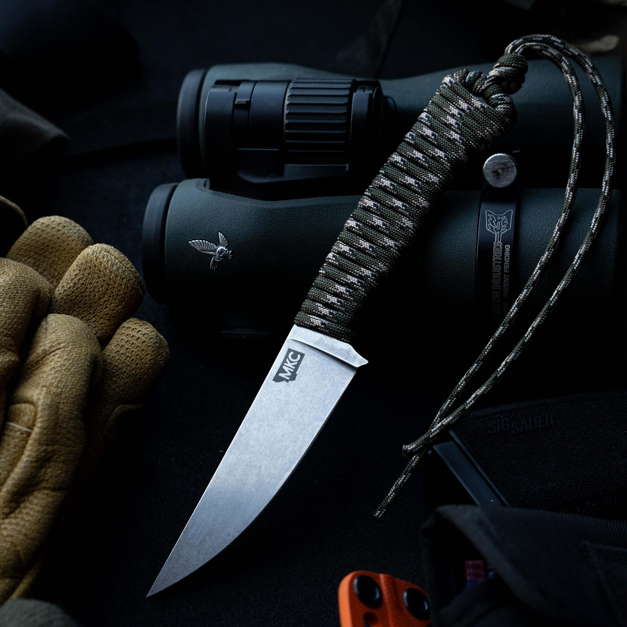 ONX Hunt Magnacut Speedgoat 2.0 knife with a paracord handle, set against outdoor gear like binoculars and gloves.