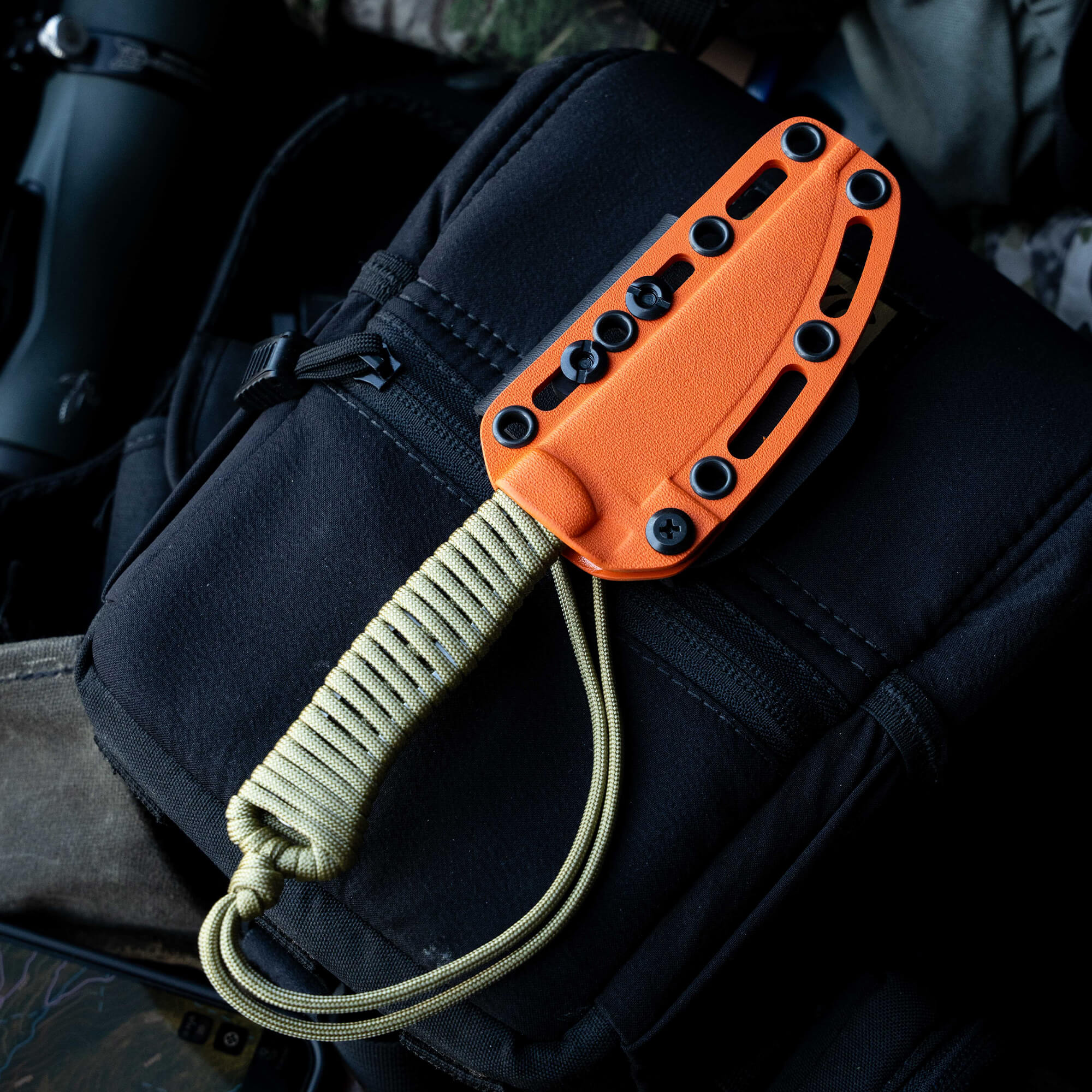 ONX Hunt Magnacut Speedgoat 2.0 knife with orange handle and sheath on a black tactical bag, ideal for outdoor use.