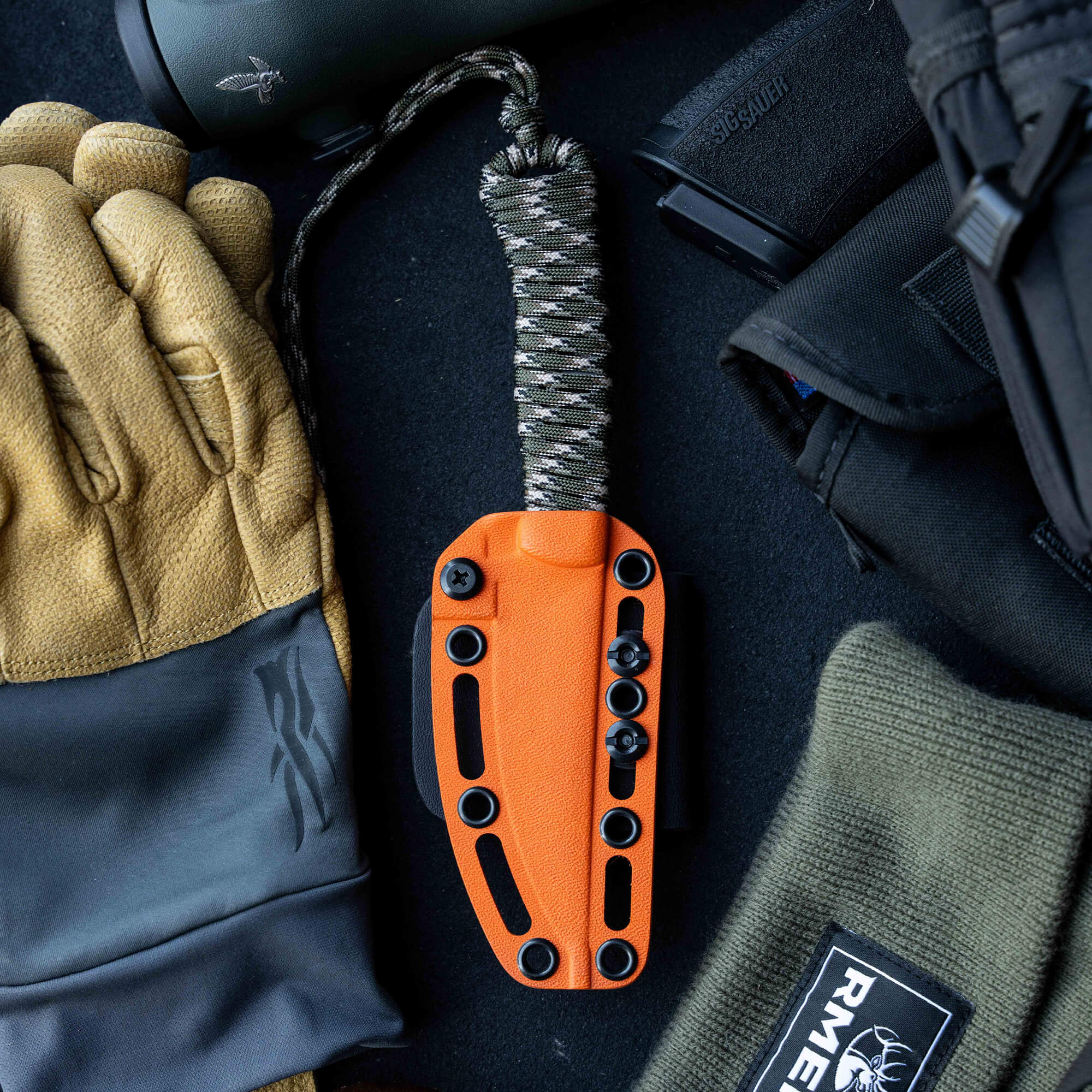 ONX Hunt Magnacut Speedgoat 2.0 knife with orange handle, surrounded by gloves and tactical gear, ideal for outdoor use.