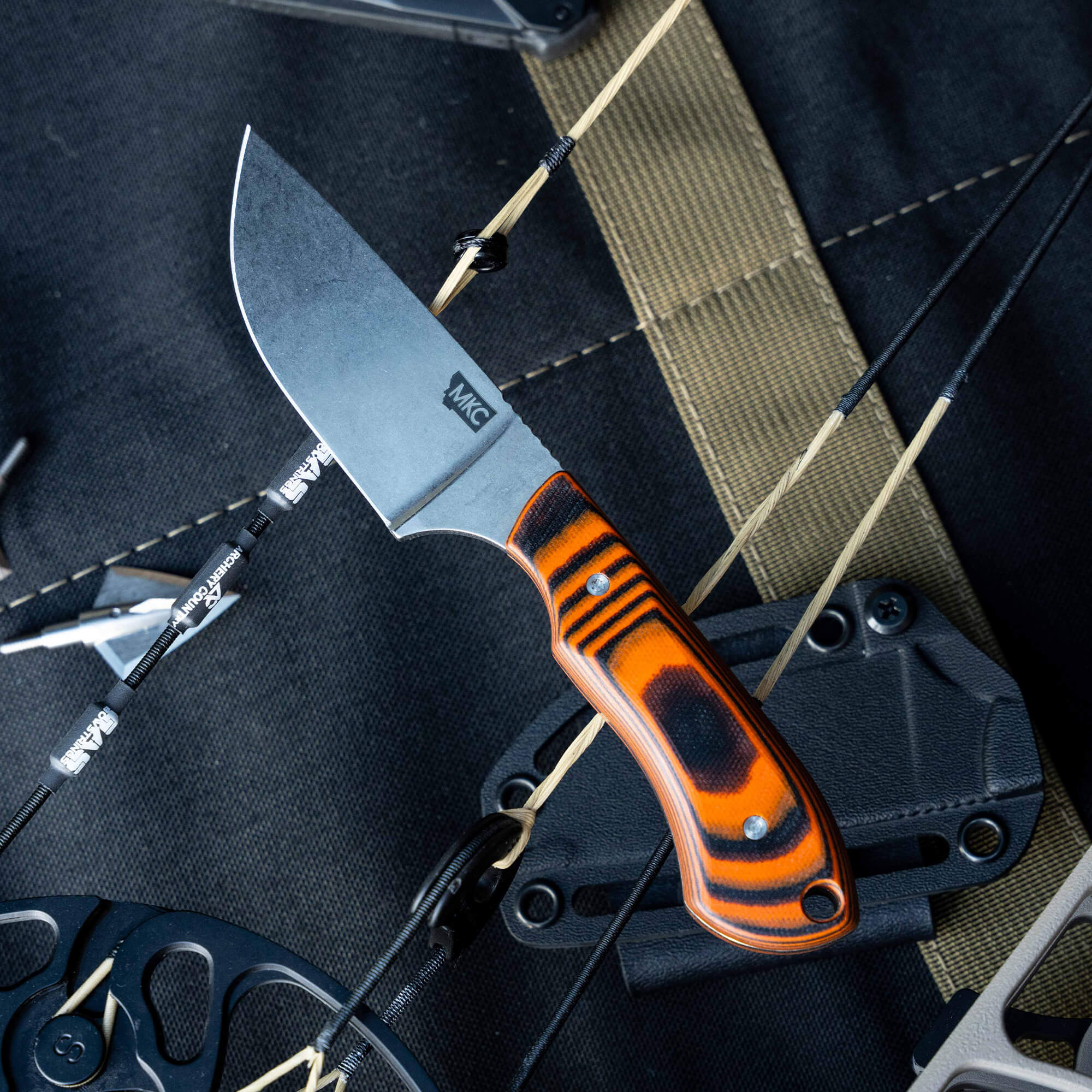Montana Knife Company's Live Wild Elk Knife features a sleek blade and striking orange and black handle, designed for outdoor enthusiasts.