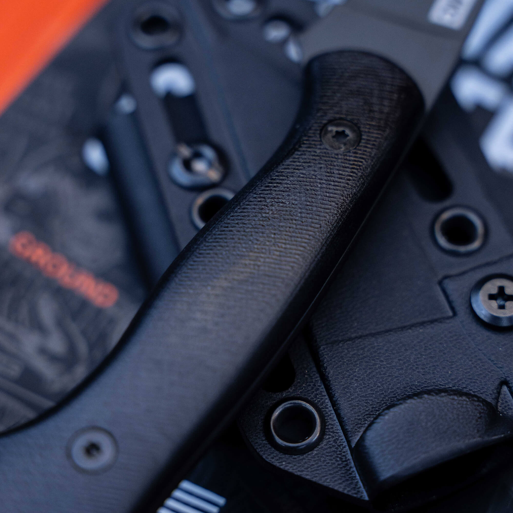 Close-up of the BLACKFOOT 2.0 folding knife in black, featuring a textured handle and a sheath with adjustable screws.