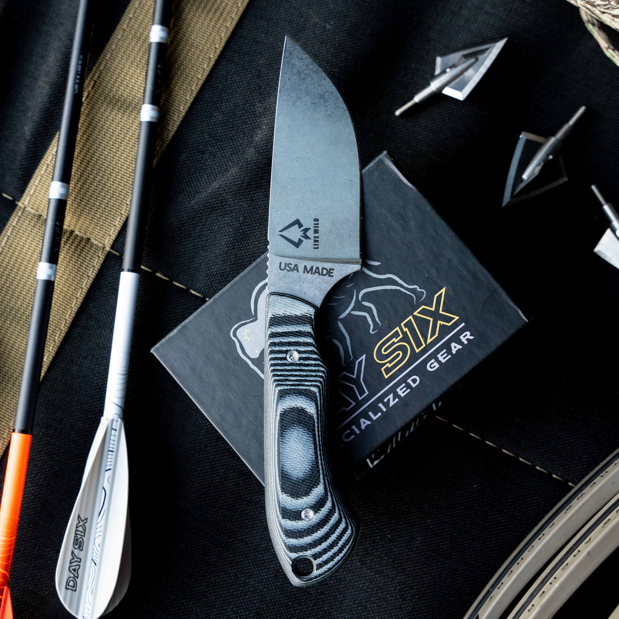 Montana Knife Company's Live Wild Elk Knife, a USA-made fixed blade, displayed with archery gear and packaging.
