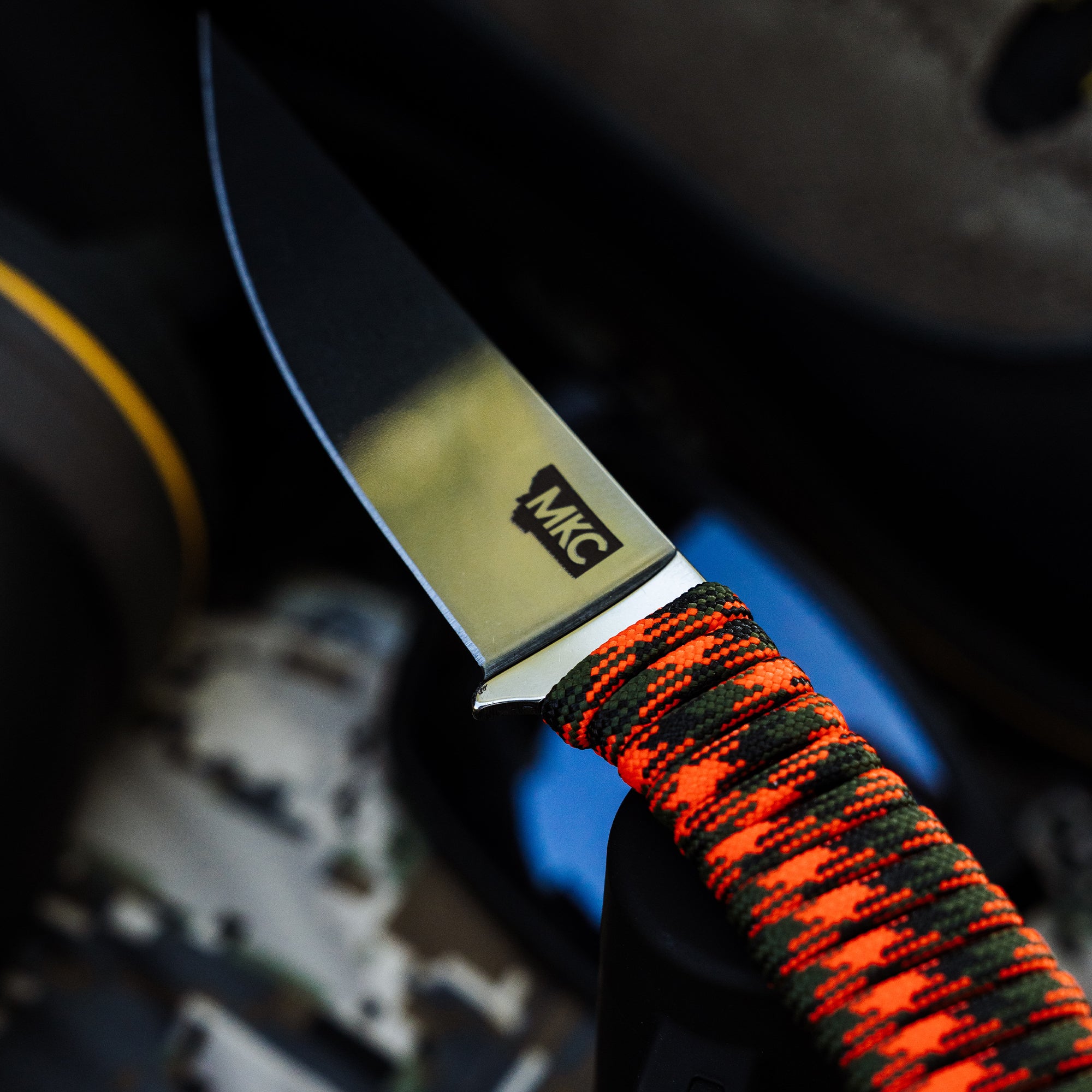 Close-up of the ONX HUNT Mini-Speedgoat 2.0 knife with a stainless steel blade and vibrant orange and green paracord handle.