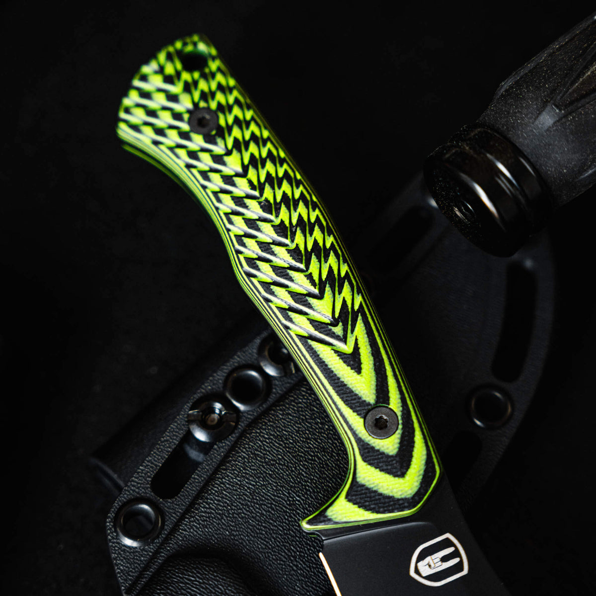 Close-up of the TRIUMPH PRO knife featuring a neon green and black patterned handle, showcasing its ergonomic design.