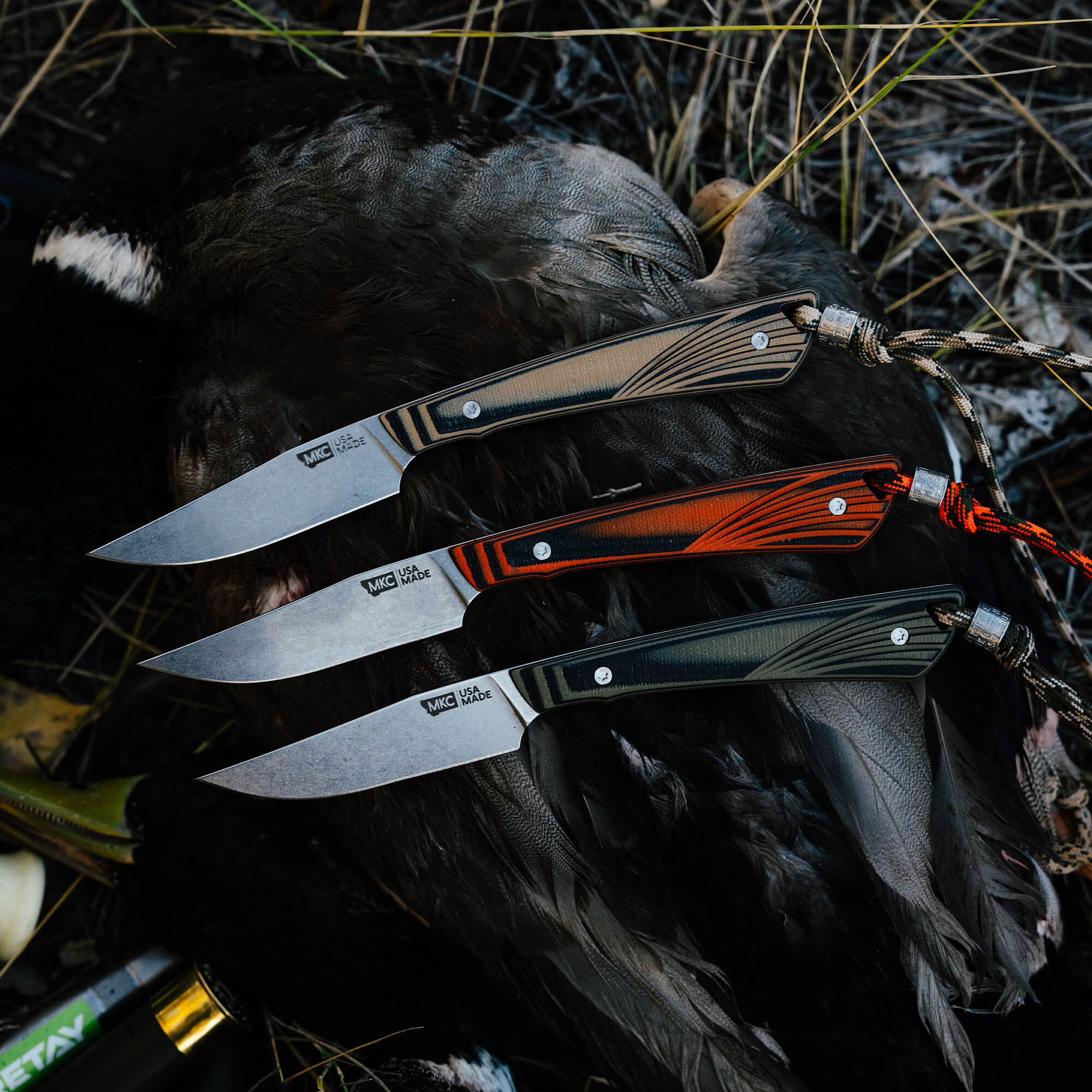 Three CHÊNE Freezout knives displayed on a duck, showcasing unique handle designs and sharp blades, ideal for outdoor use.