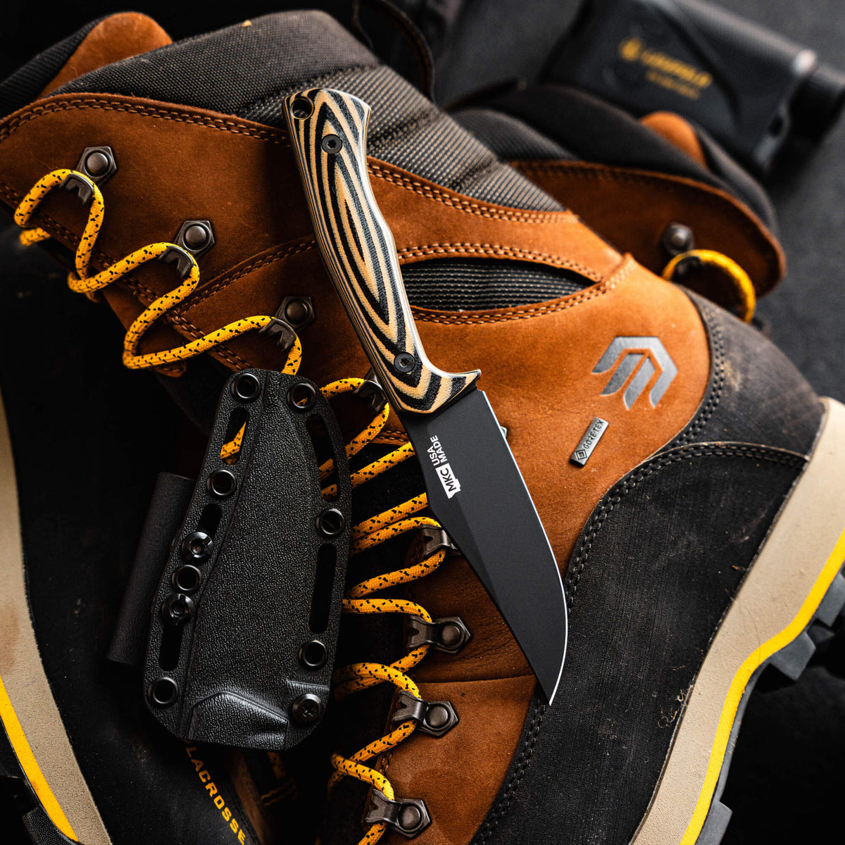 Triumph Pro knife in tan and black resting on a rugged boot, showcasing its durable design for outdoor use.