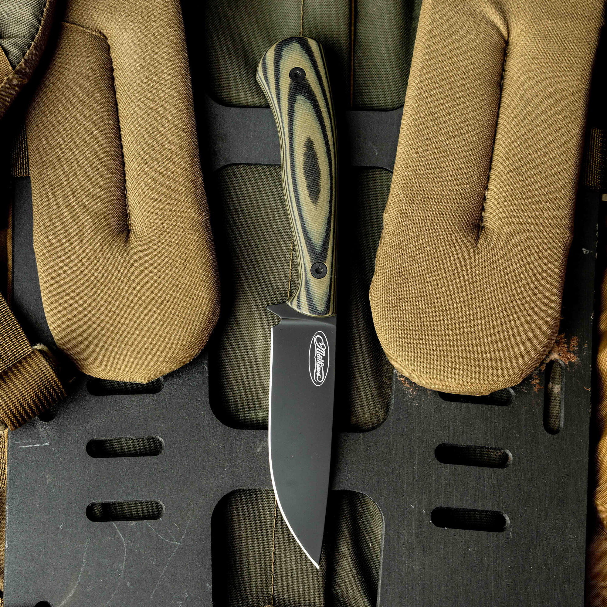 Mathews Archery MKC Whitetail knife on a tactical background, featuring a sleek black blade and textured green handle.